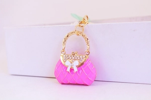 Macro shot of pink enamel handbag keychain with rhinestones and white bow detail
