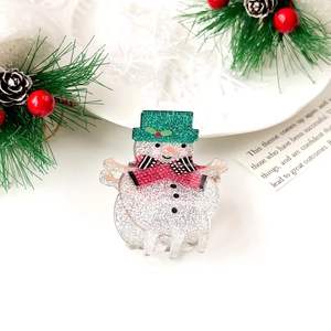 Detailed view of snowman hair claw clip with green glitter hat and red scarf accent