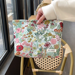 Floral jacquard cosmetic bag with handle shown in a natural cafe setting