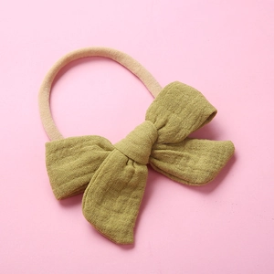 Close-up of mustard green muslin cotton bow headband showing soft fabric texture