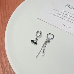 Detail shot of asymmetric cherry drop earring and chain link on white ceramic tray