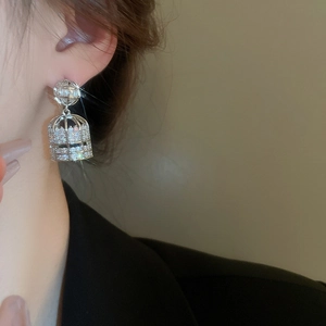 Detailed view of silver birdcage earrings with zircon pavé and pearls on model