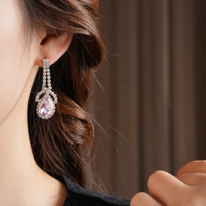 Detail of elegant silver teardrop earrings featuring pink gemstones and sparkling crystals