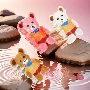 Three cute teddy bear hair claws in pink, white, and brown on a water ripple background