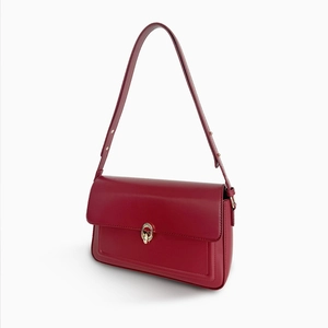 Detail view of the vintage red leather shoulder bag with an oval gold metal buckle clasp