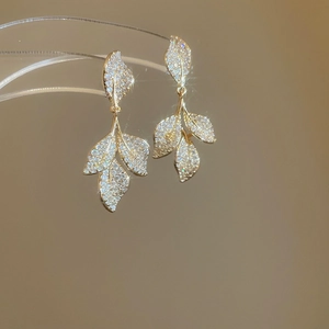 Detail of gold leaf tassel earrings with sparkling zircon stones on a display stand