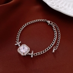 Détail du pendentif en zircon carré sur une chaîne argentée et tissu en soie
