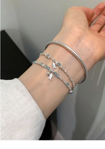 Close-up of beaded bracelets with freshwater pearls and matte silver fish pendants