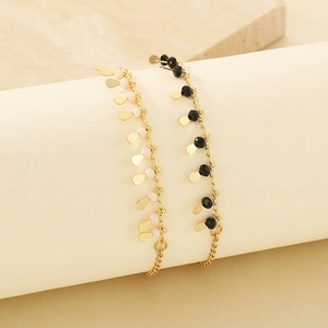 Detailed view of a gold-plated chain bracelet with pink beads and teardrop pendants