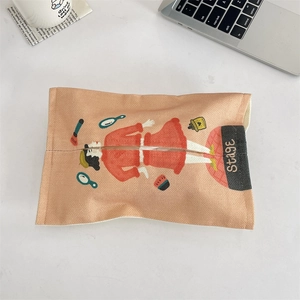 Flat lay of retro orange fabric tissue cover with character print on a desk background