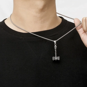 Detail of Thor's Hammer Mjolnir pendant with Valknut symbol on a steel chain worn by model