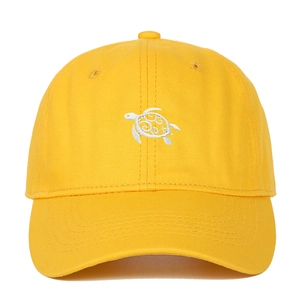 Close-up of a yellow cotton baseball cap featuring white sea turtle embroidery and stitching