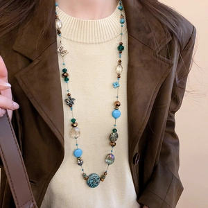 Detail of bohemian layered beaded necklace with turquoise stones and butterfly pendant