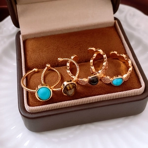 Macro detail of 18k gold plated tiger eye and turquoise rings in a jewelry box