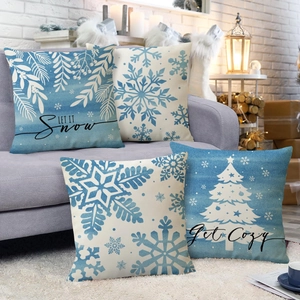 Set of 4 blue and white snowflake Christmas linen pillow covers on a cozy sofa