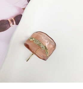 Detail of square resin hair clip in transparent amber pink with gold metal stripe inlay