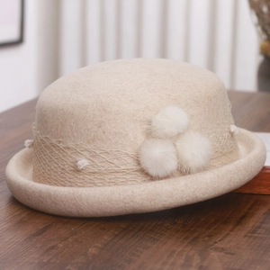 Close-up of beige wool beret with delicate mesh ribbon and soft white pom-pom details