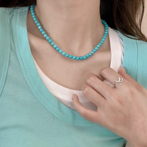 Bohemian turquoise beaded necklace with silver bow ring on a female model