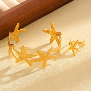 Macro detail of golden starfish jewelry set with realistic textured surface on sand