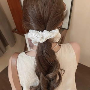 Vue détaillée d'un chouchou en dentelle blanche avec étiquette sur coiffure élégante