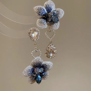 Dettaglio di orecchini a fiore con ricamo blu e grandi cristalli color champagne eleganti