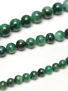 Macro shot of green mica round beads showing natural stone texture and glossy finish
