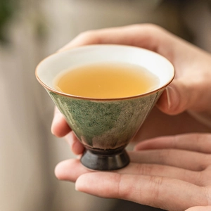 Hand-held vintage kiln-baked emerald ceramic tea cup with artistic star glaze finish