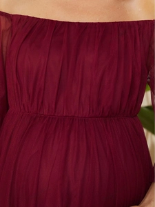 Detail of waist pleats and tulle fabric on a burgundy off-shoulder evening dress