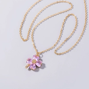 Detail of pink heart-shaped crystal clover pendant on a fine golden necklace chain