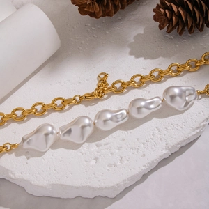 Détail d'un collier en perles baroques et chaîne plaquée or 18K sur pierre blanche
