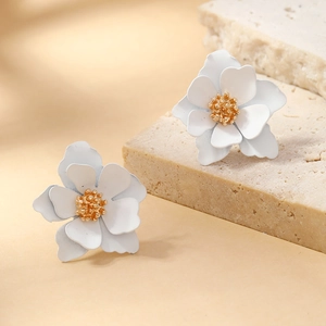 Elegant white multi-layered petal earrings with golden stamen on a stone surface