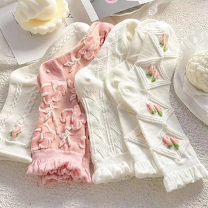 Detail von rosa und weißen Socken mit Blumenstickerei und modischem Wellensaum