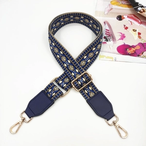 Detail of blue jacquard woven strap with navy PU leather ends and gold metal buckles