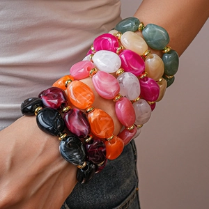 Close-up of stacked acrylic chunky bracelets with marble texture and gold beads