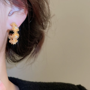 Close-up of elegant gold plated flower cluster stud earrings worn by a model