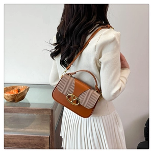 Detail of contrast stitch handbag with gold logo hardware and adjustable shoulder strap