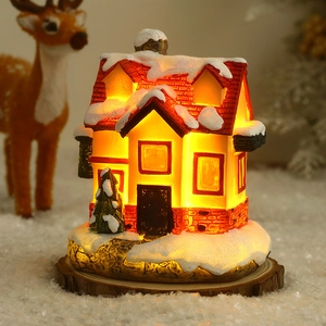 Détail d'une maison de Noël miniature lumineuse sur socle en bois avec effets de neige