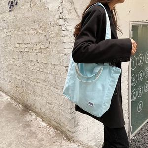 Detalle de bolso tote de lona azul claro con correas anchas en un entorno urbano moderno