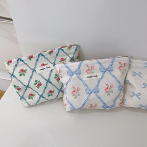 Détail d'une trousse à maquillage fleurie avec rubans bleus et motifs de roses