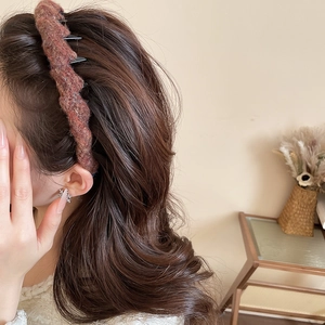 Close-up of caramel acrylic wool headband with twisted knit texture on brunette curly hair