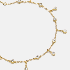 Elegant gold anklet with round cubic zirconia charms on a white background