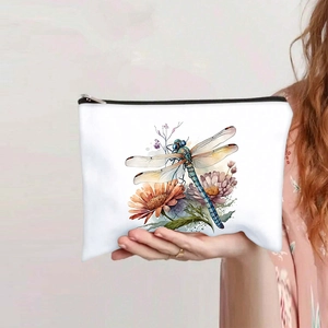 Detail of white makeup bag with colorful dragonfly and flower prints held by a model