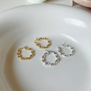 Detailed view of twisted wave hoop earrings in polished gold and silver 925 sterling silver