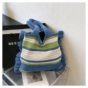 Detail of hand-knitted tote bag with blue, green, and white stripes and ruffle edges