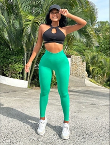 Women in bright green high waist seamless yoga leggings and black halter sports bra outdoors