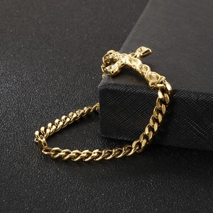 Macro shot of gold-plated cross pendant on a thick Cuban link bracelet for men