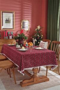 Close-up of red and black plaid tablecloth featuring decorative white pompom tassel fringe