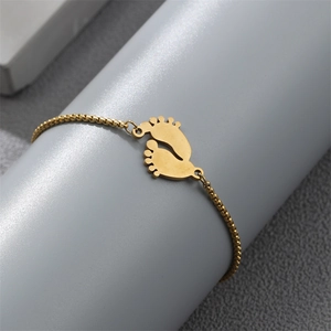 Macro view of gold stainless steel ball chain bracelet with a baby footprint charm