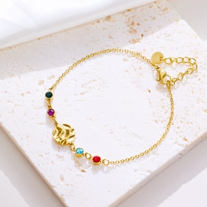 Detailed view of gold evil eye bracelet with colorful stones and hammered metal pendant