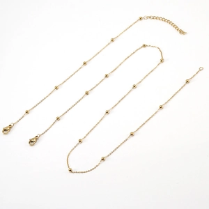 Detail view of two gold stainless steel beaded necklaces with lobster clasps on white base